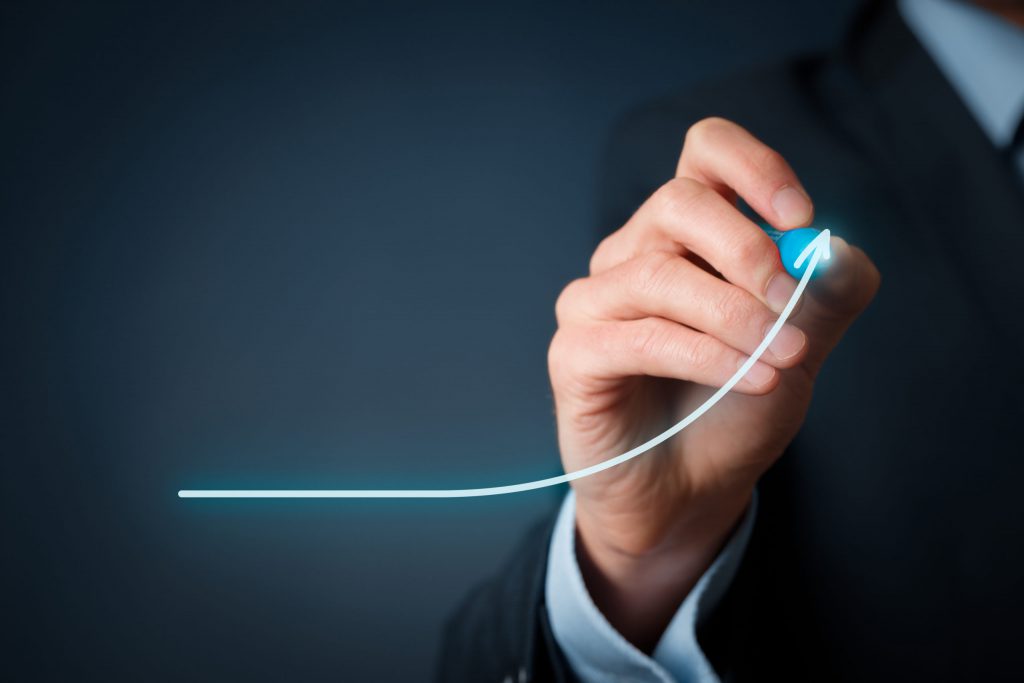Development and growth concept. A business man is drawing an arrow that is curving upwards. He is illustrating the concept of employer savings.